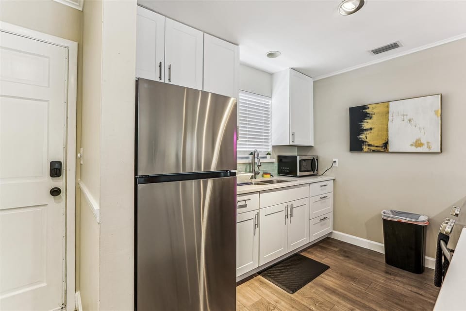 - Fully equipped kitchen featuring stainless steel refrigerator and microwave  
- White cabinetry with plenty of storage space for extended stays  
- Clean modern layout designed for guest convenience and comfort 