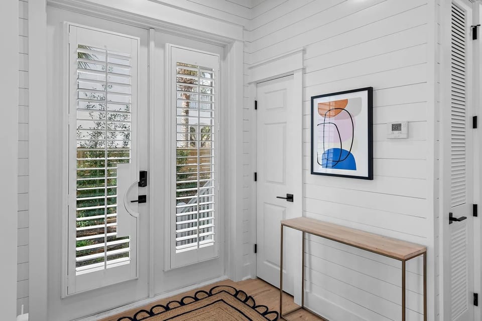Welcoming entryway w/ glass doors, natural light, and clean coastal finishes