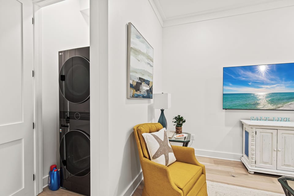 Relax in your cozy seating area with convenient in-unit laundry nearby and coastal artwork setting the perfect beachy mood.