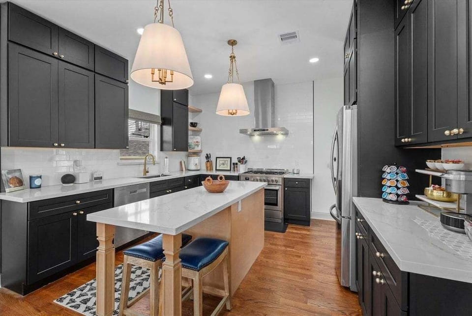 Fully equipped modern kitchen with island, stainless steel appliances, and pendant lighting