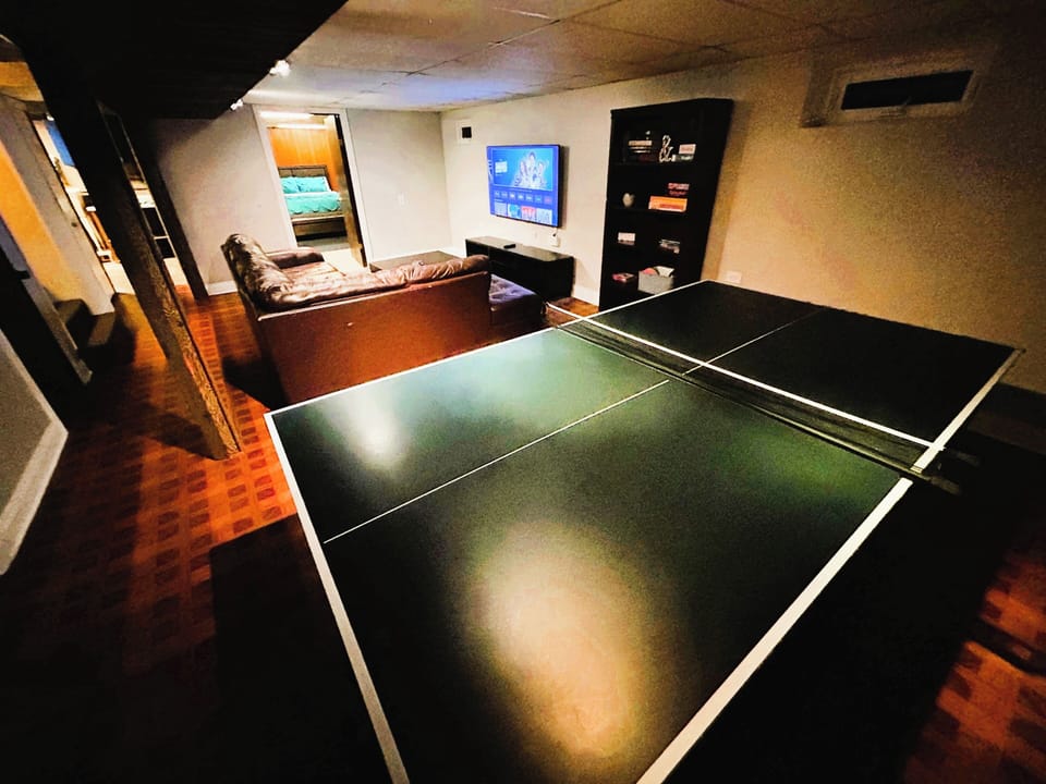 Basement with sofa, TV, and ping pong for fun.