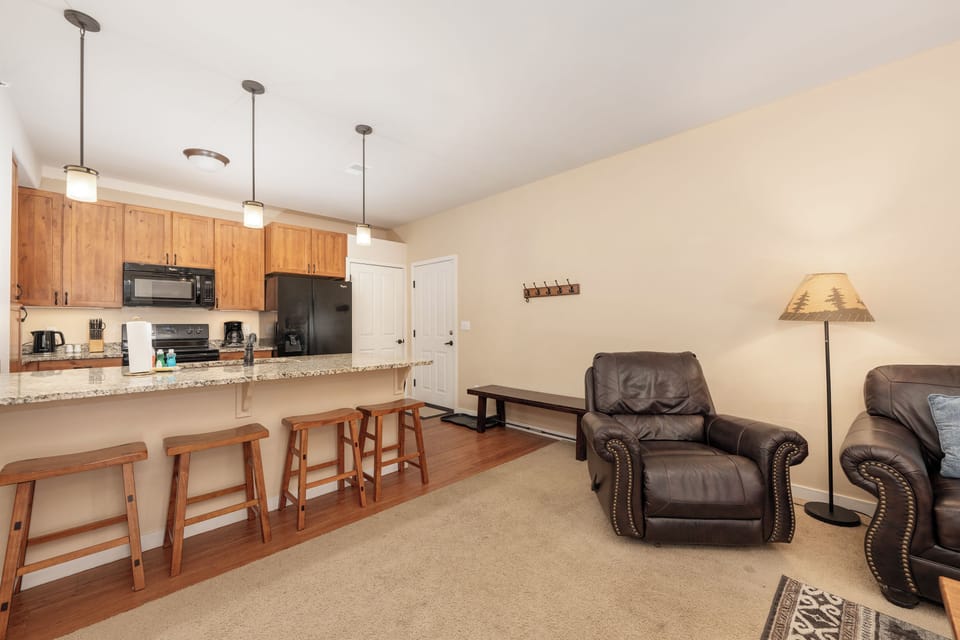 Relax in your spacious open-concept living area at Ten Mile G-201 with granite countertops, full kitchen, and comfortable leather seating for memorable evenings.