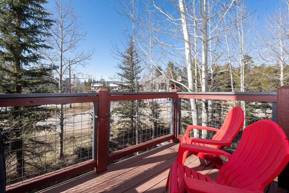 Relax in vibrant red Adirondack chairs on your private deck, surrounded by towering aspens and peaceful mountain views.