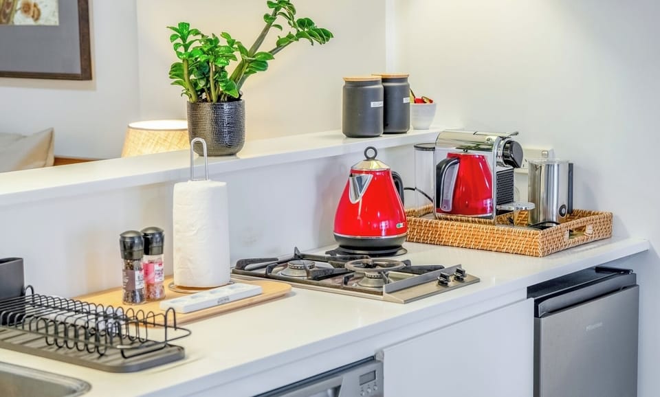 A functional and tidy kitchen workspace equipped with modern appliances and a red kettle.