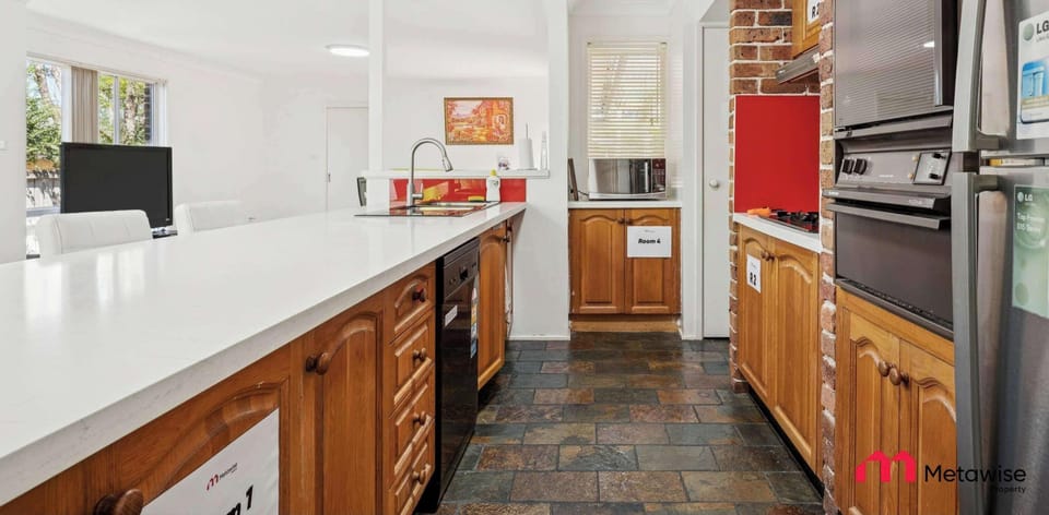 Shared kitchen with long countertop, wooden cabinetry, and cooking appliances.
