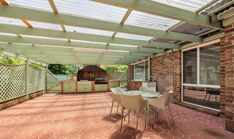 Covered outdoor patio with tiled flooring and outdoor seating.