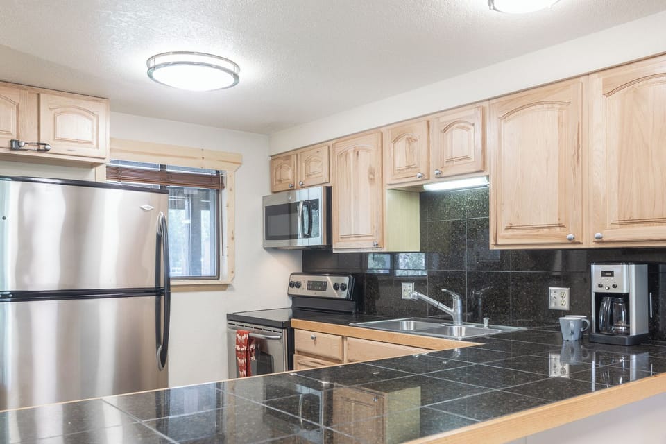 Your fully equipped kitchen features granite countertops, stainless steel appliances, and warm wood cabinetry for effortless meal preparation.