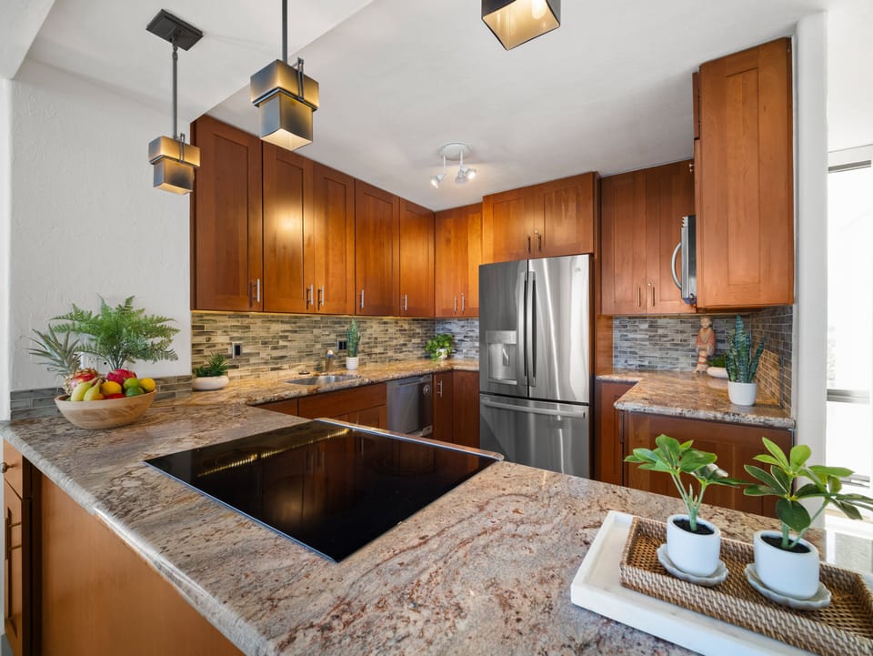 Cook like a chef in this fully equipped kitchen featuring granite countertops, stainless steel appliances, and modern pendant lighting in paradise.