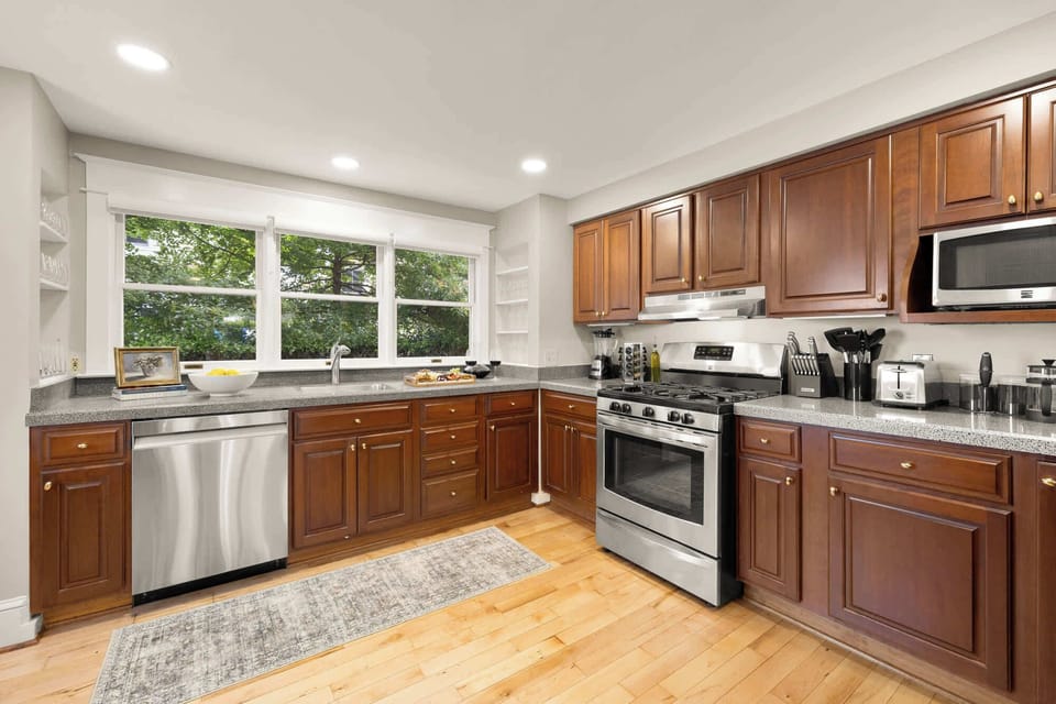 Enjoy cooking in a fully equipped kitchen featuring stainless steel appliances, spacious wooden cabinetry, and plenty of natural light. Includes dishwasher, stove, and relaxing breakfast views.