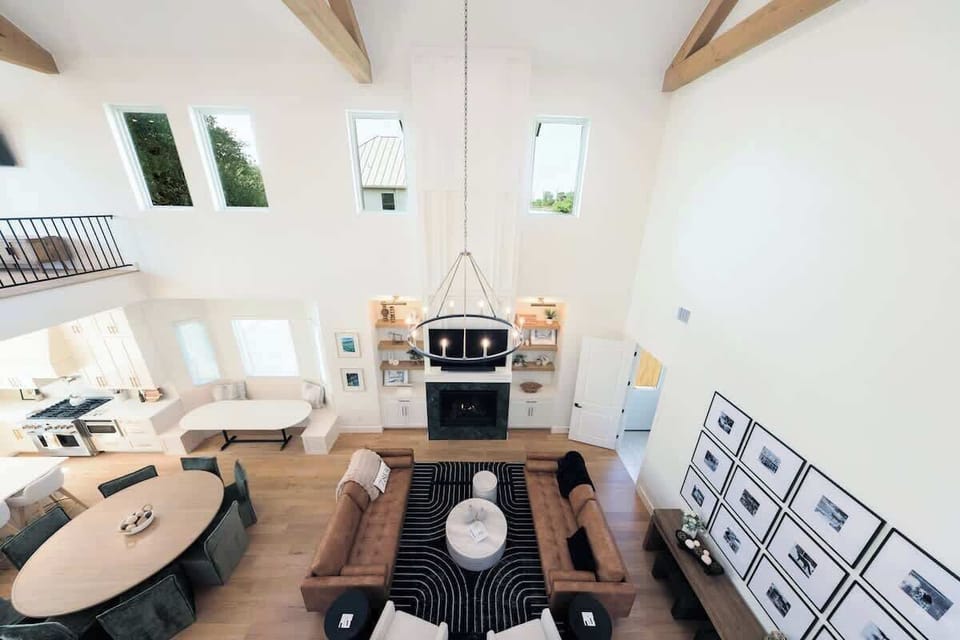 Soaring ceilings, stunning design ✨ This open-concept living space blends comfort and elegance with natural light, exposed beams, a cozy fireplace, and room for everyone to gather in style.