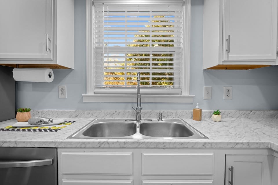 Modern kitchen with stainless appliances, fridge & coffee makers.
