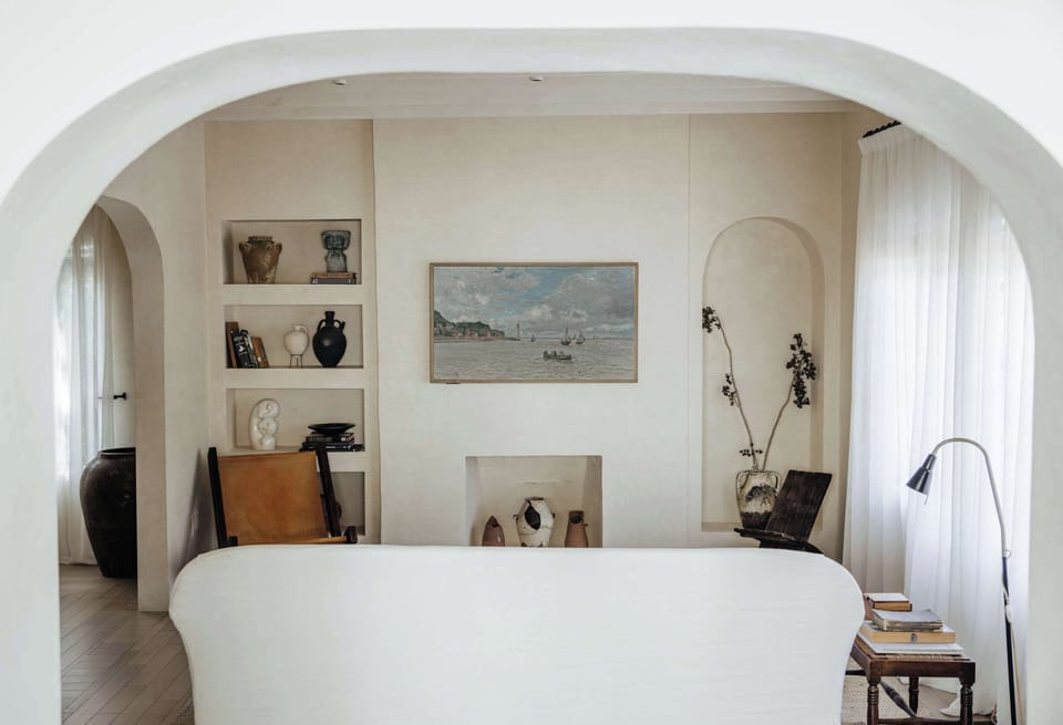 Living room featuring a frame TV, custom couch, vintage book shelves and arched hallway