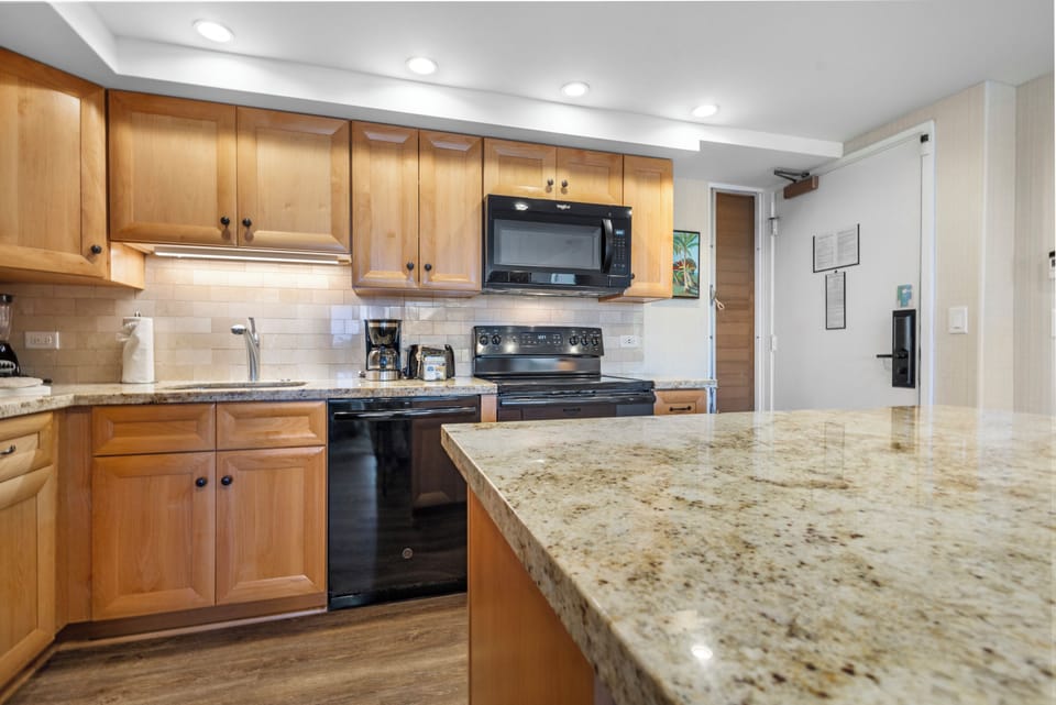 Prepare your favorite meals in this fully equipped kitchen, featuring granite counters, warm wood cabinetry, modern appliances, and all the essentials for a comfortable stay.