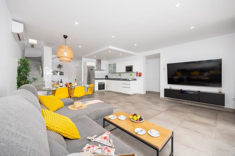 Open-plan living room with sofa, dining area, kitchen, A/C, WiFi internet, and satellite TV