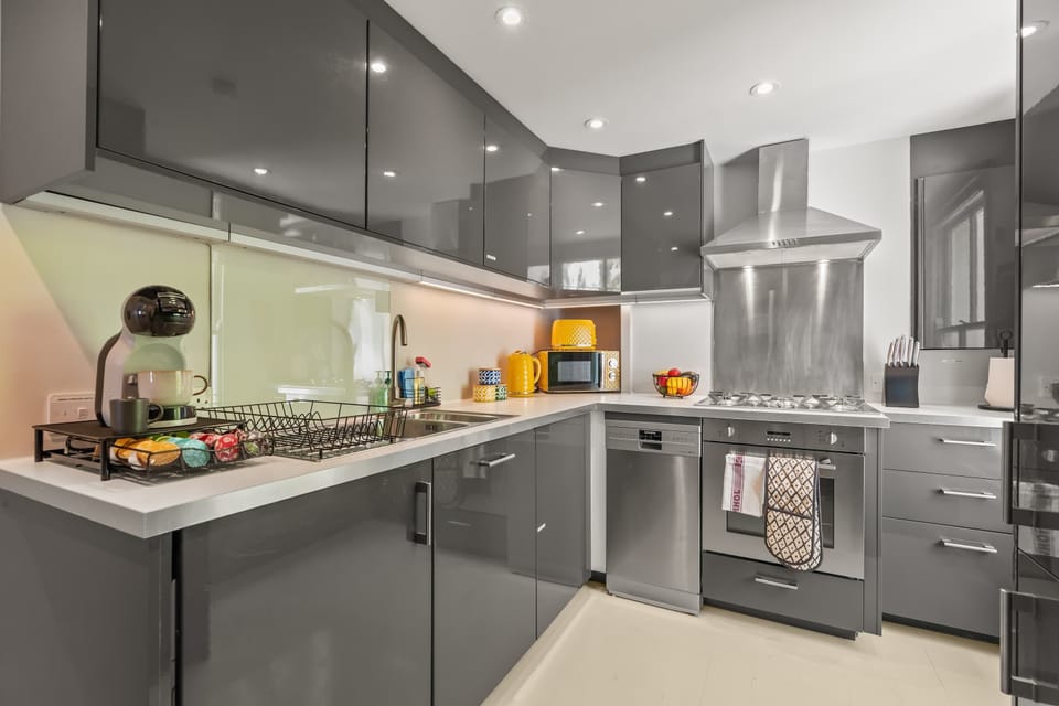 This sleek grey kitchen, accented with cheerful pops of yellow, is fully equipped with everything you need to cook comfortably away from home. A stylish and practical space for enjoying home-cooked meals during your London stay.