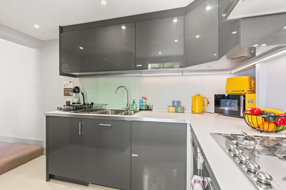 This sleek grey kitchen, accented with cheerful pops of yellow, is fully equipped with everything you need to cook comfortably away from home. A stylish and practical space for enjoying home-cooked meals during your London stay.