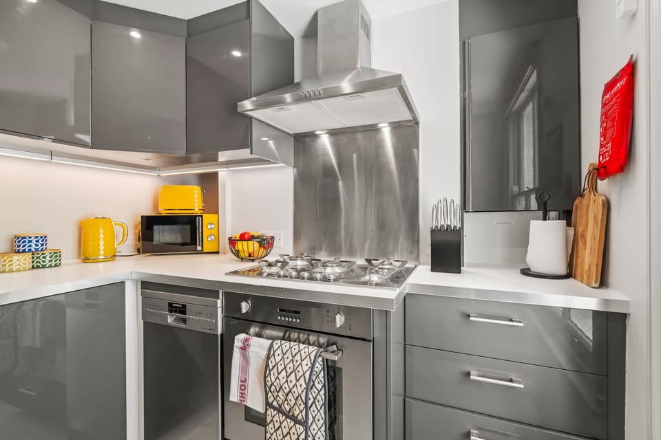 This sleek grey kitchen, accented with cheerful pops of yellow, is fully equipped with everything you need to cook comfortably away from home. A stylish and practical space for enjoying home-cooked meals during your London stay.