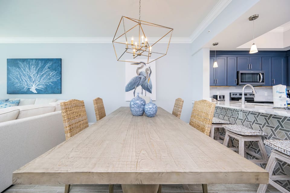 Gather around the spacious dining table, accented by coastal decor and a striking chandelier for memorable meals