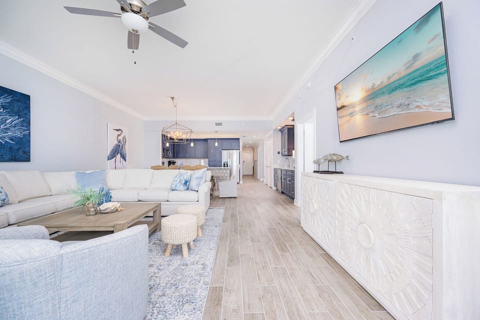 Unwind in this stylish living area with plush seating, a large TV, and coastal decor, perfect for relaxation