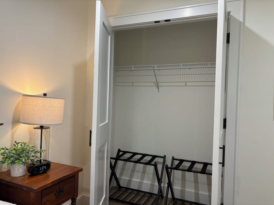 Bedroom closet with luggage racks and hangers.