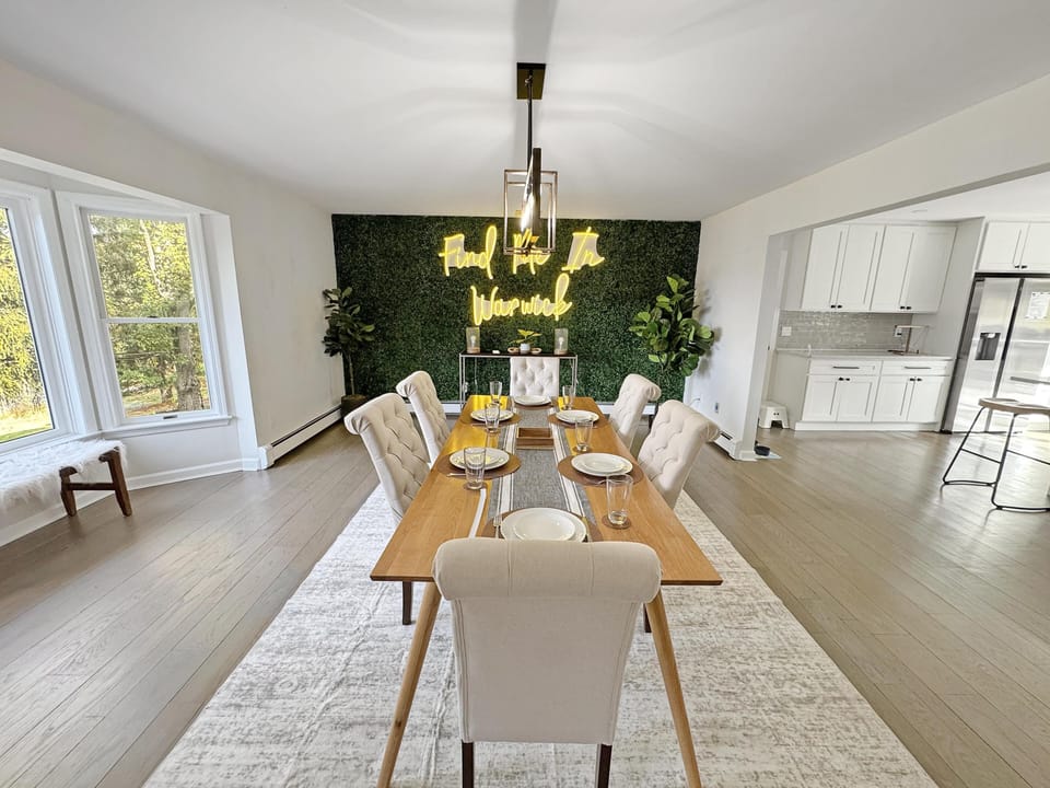Bright dining room with lush green accent wall and modern chandelier