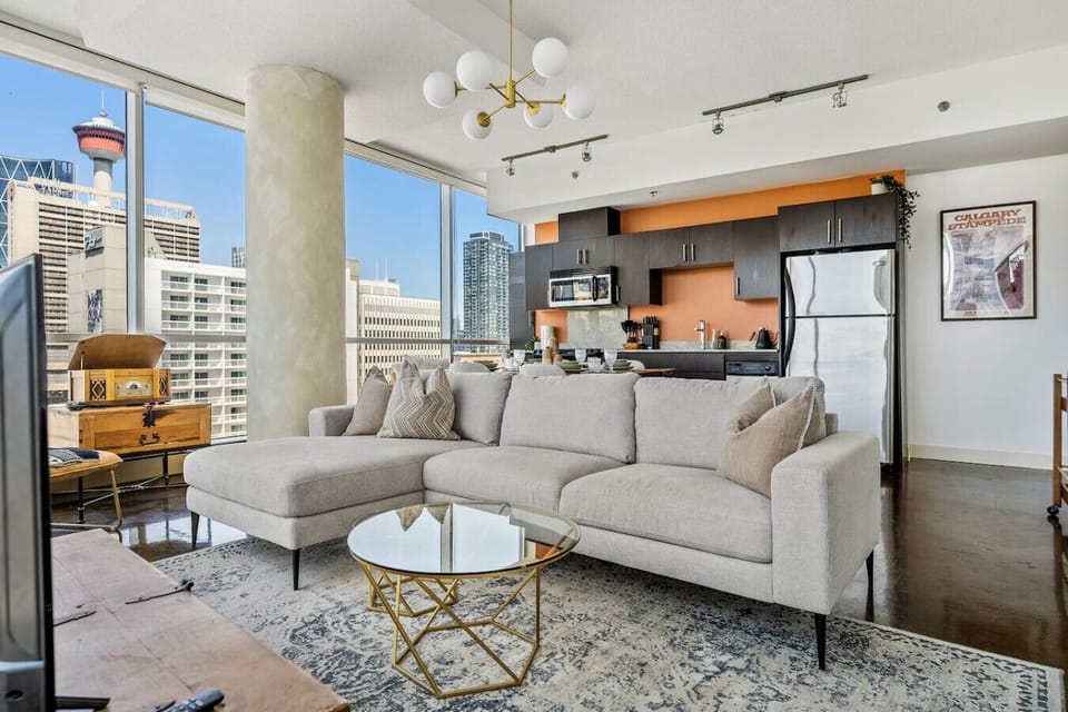 Living room with a 55` Smart TV, PS4, a record player and floor-to-ceiling, NW-facing windows with views of the Calgary tower & city skyline.