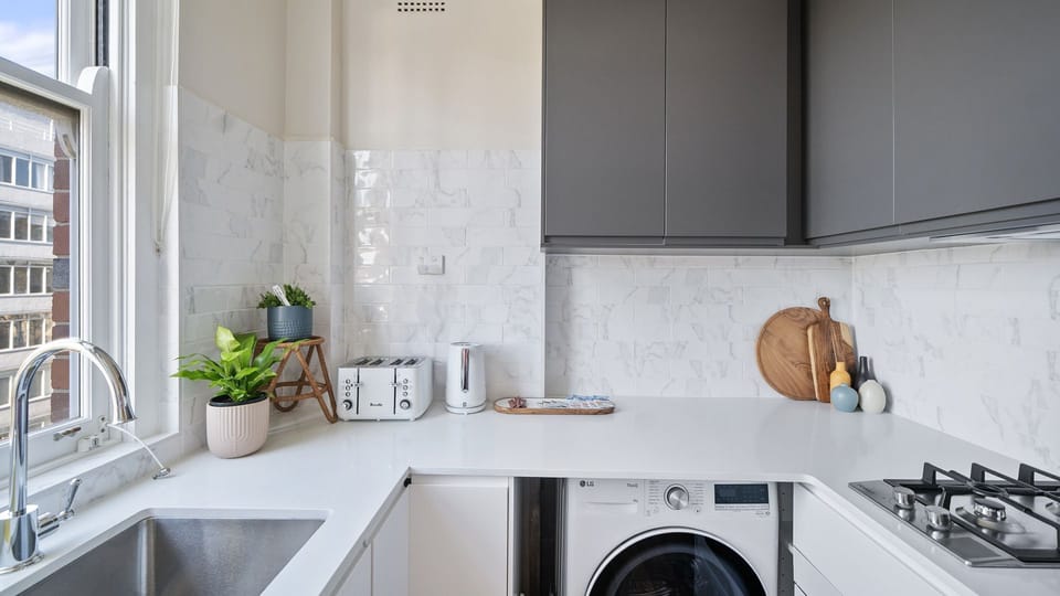 Smart & Sleek Compact Kitchen - This clever kitchen layout packs a major design punch with its striking contrast of matte charcoal cabinets and bright white countertops.