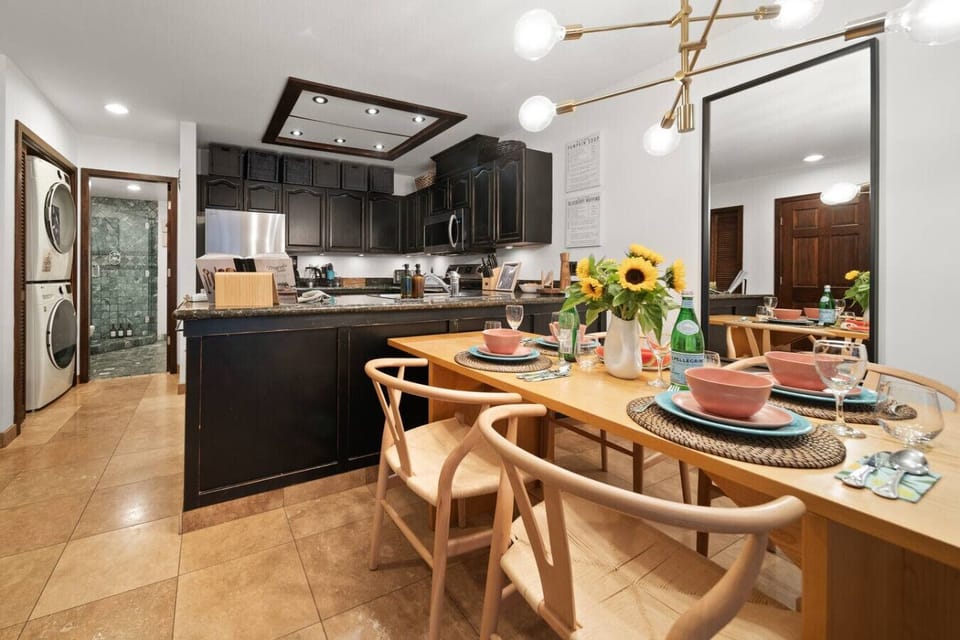 Warm dining area with sunlit décor beside a stylish modern kitchen.