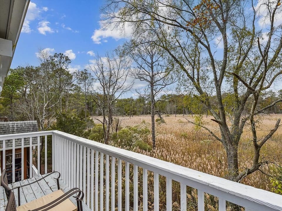 Relax on the upper balcony and take in the picturesque views of the wetlands, framed by trees, offering a peaceful retreat to enjoy nature's beauty.