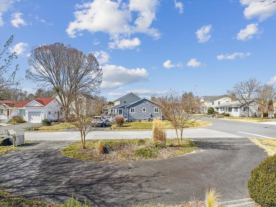 Wide driveway with manicured landscaping and a peaceful neighborhood backdrop—ideal for a tranquil arrival.