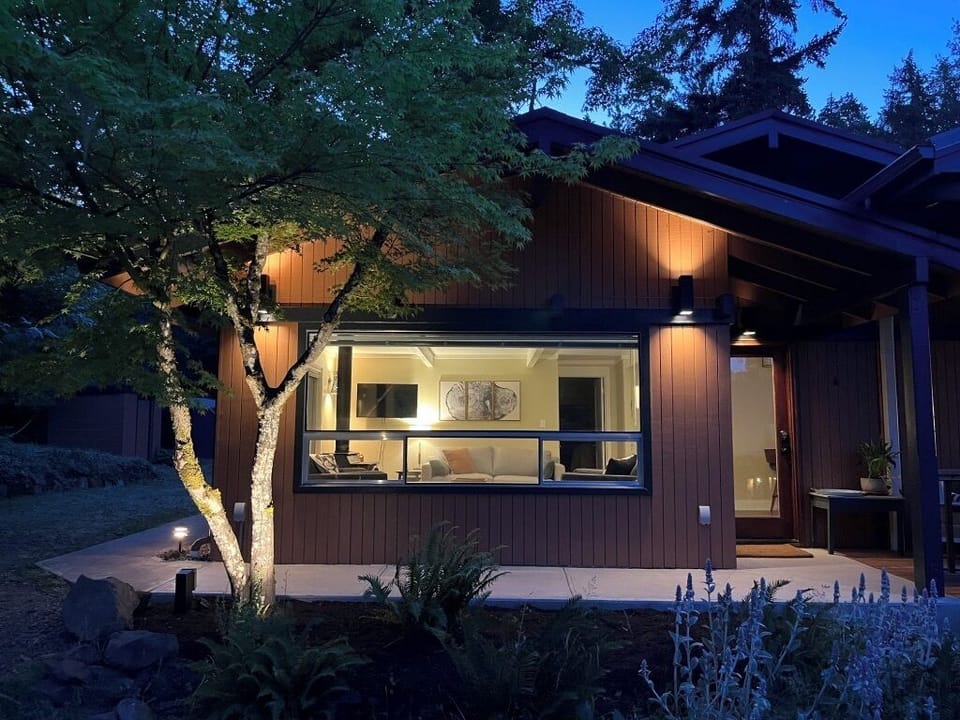 Well lit exterior walkway looking into the living room and covered main entry.