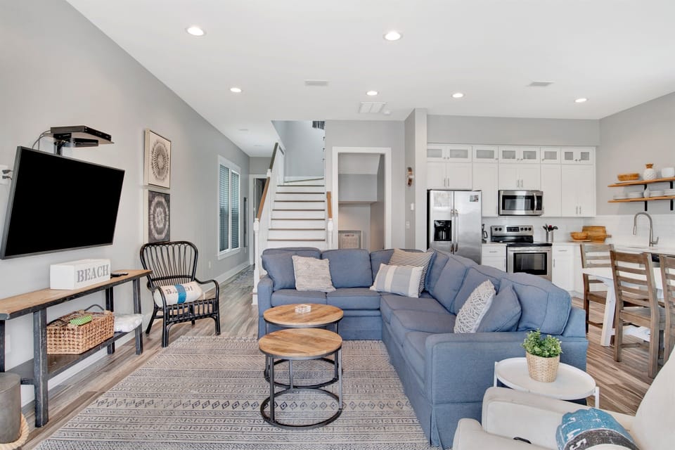 The open living room flows seamlessly into a bright staircase leading upstairs, combining comfort and coastal style with a touch of island elegance.