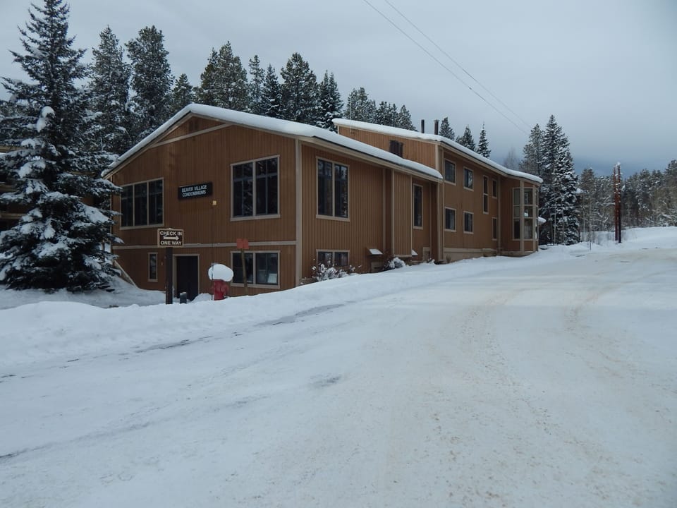 Charming wood-sided lodge nestled among snow-covered evergreens, offering a perfect winter retreat in pristine mountain surroundings.