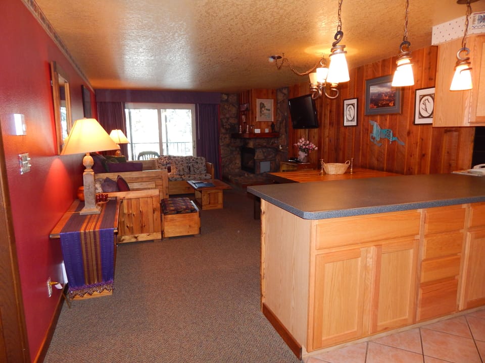 Cozy mountain retreat with warm wood touches, stone fireplace, and open kitchen - your perfect ski lodge escape awaits.