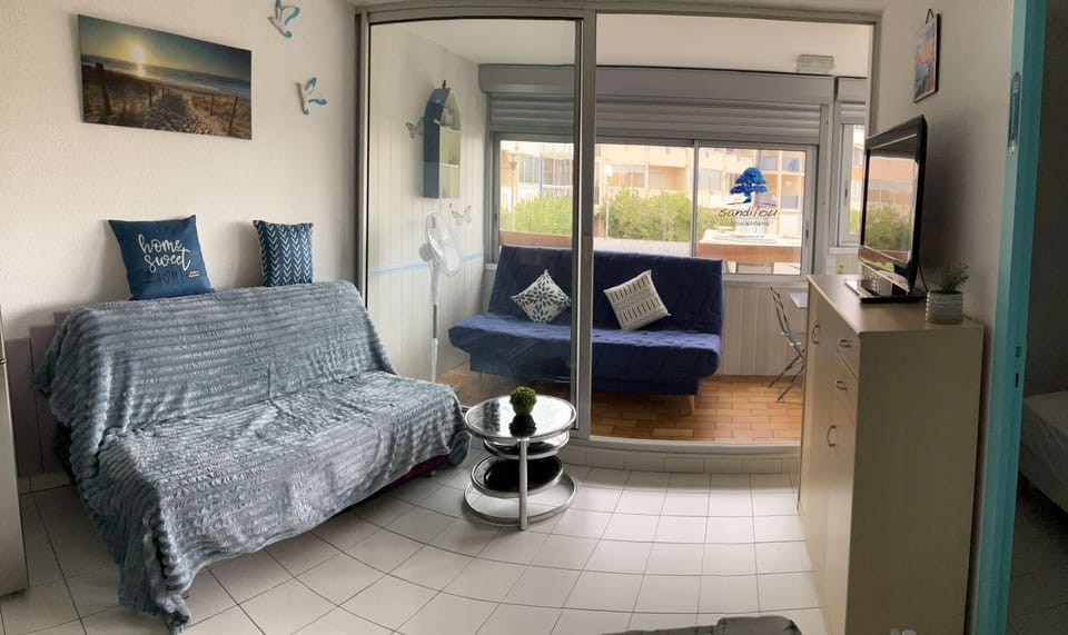 Relaxation area with a convertible sofa, a private balcony with a table and two chairs, plus another convertible sofa.