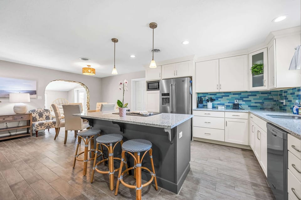 Modern kitchen with a large island and blue tile backsplash for family-friendly gatherings.