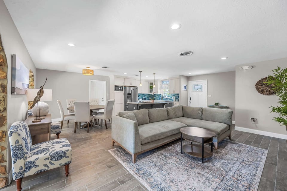 Open-concept living and dining area with a modern kitchen featuring a blue tile backsplash.