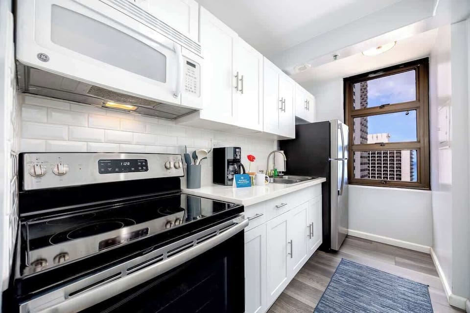 Prepare your favorite meals in this well-appointed kitchen, featuring modern white cabinetry, essential appliances including a GE microwave and electric range, and ample counter space for your culinary needs.