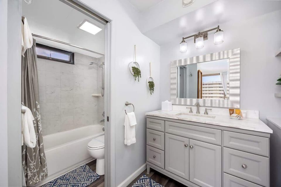 Refresh in this bright and modern bathroom, featuring a stylish vanity with ample counter space, a large mirror, and a convenient shower-over-tub combination, all designed for your comfort.