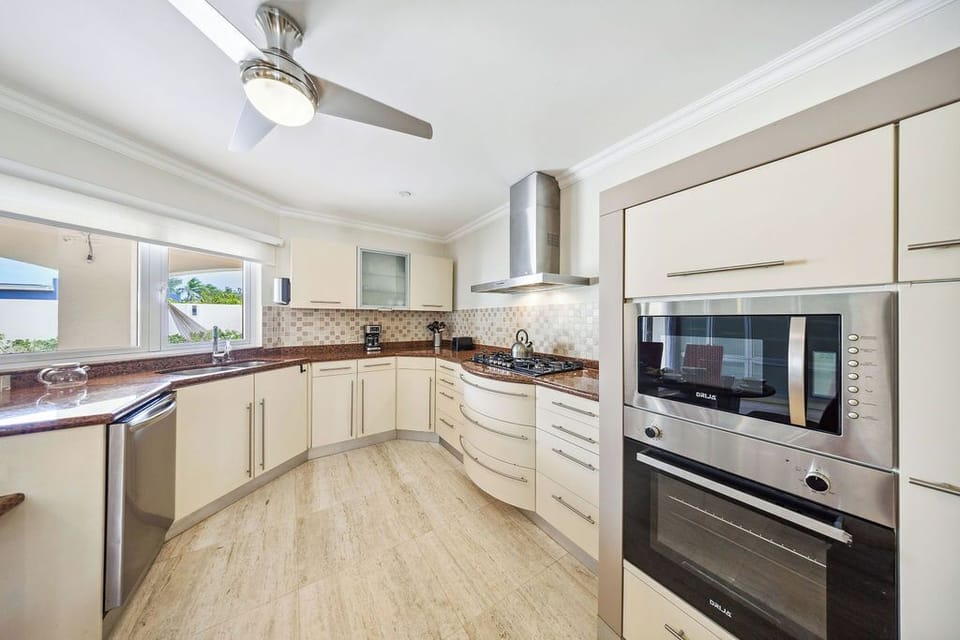 Your gourmet kitchen awaits with polished granite counters, modern appliances, and tropical breezes flowing through wide windows as you prepare island-inspired meals.