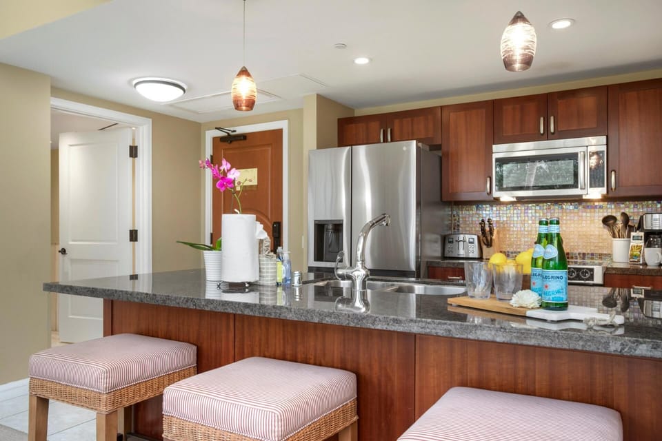 Stylish gourmet kitchen with granite countertops, stainless steel appliances, and bar seating. HKH-114