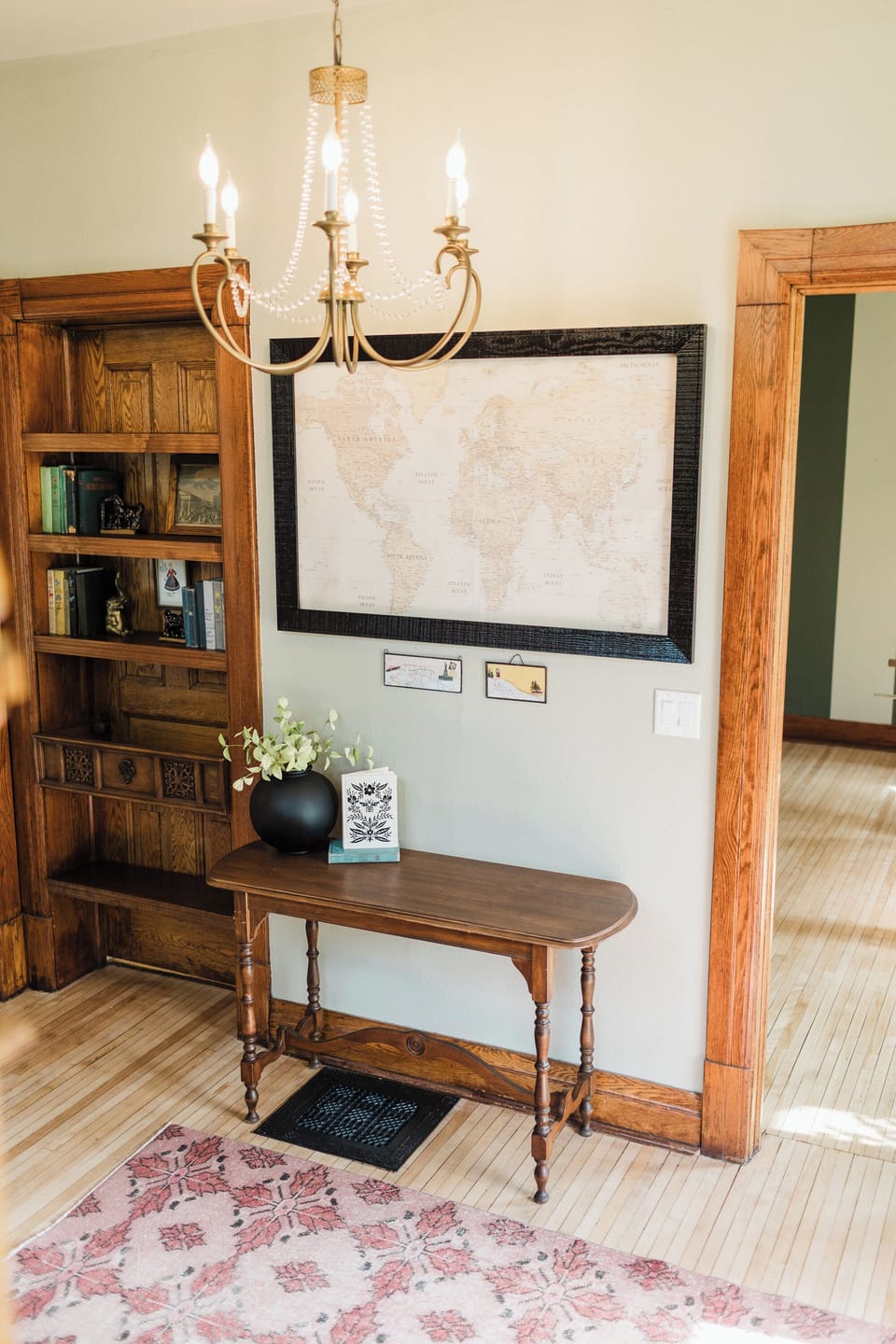 Welcome to your home away from home. This charming entry features a world map to inspire your next adventure, a vintage table with local tips, and a hidden bookshelf nook for a touch of character and curiosity. 