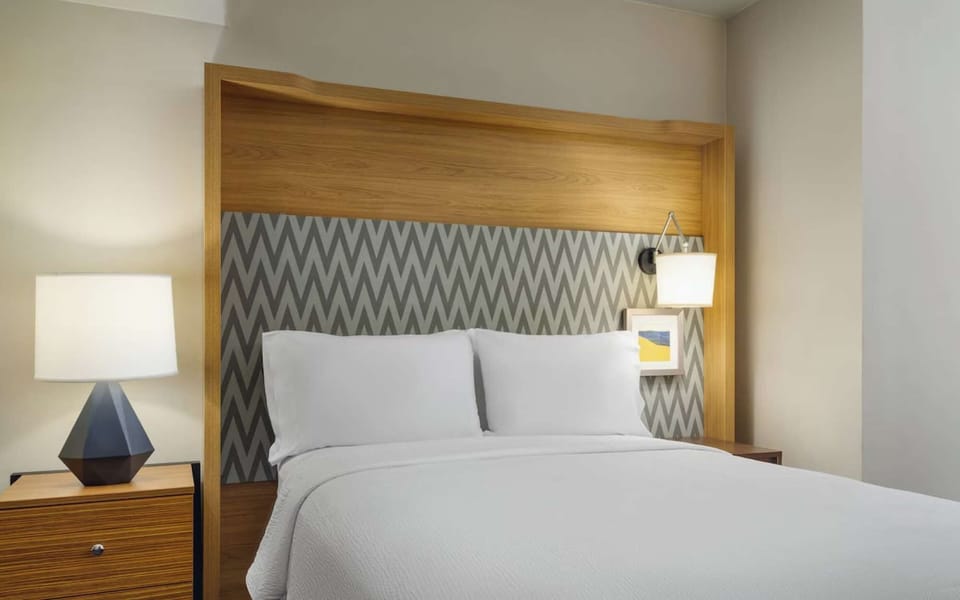 Cozy king bed with wood headboard and chevron wall accent