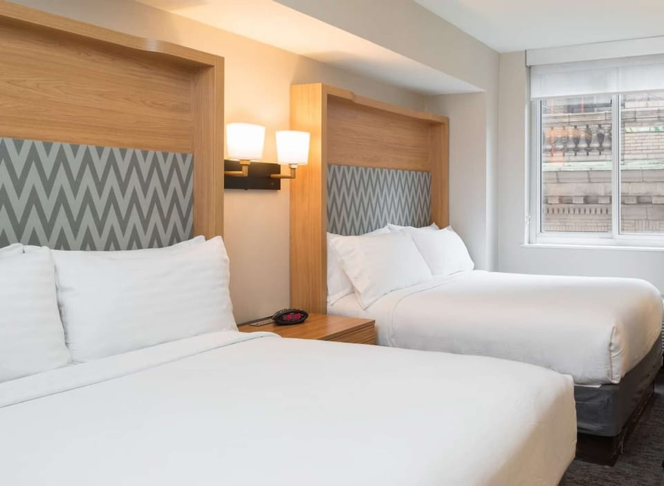 Bright room with two beds, soft lighting, and large window