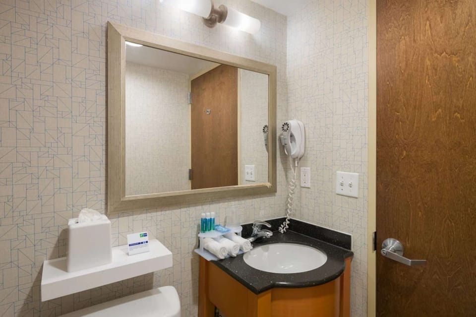 Bathroom with vanity mirror, wall hair dryer, and fresh towels