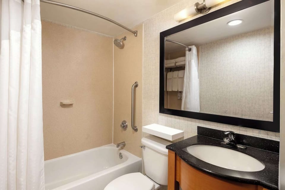 Bathroom with tub, large mirror, and curved shower curtain rod