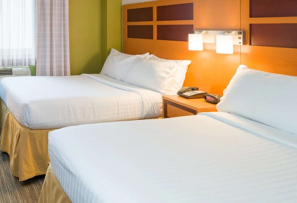Two double beds with wood headboards and bedside phone