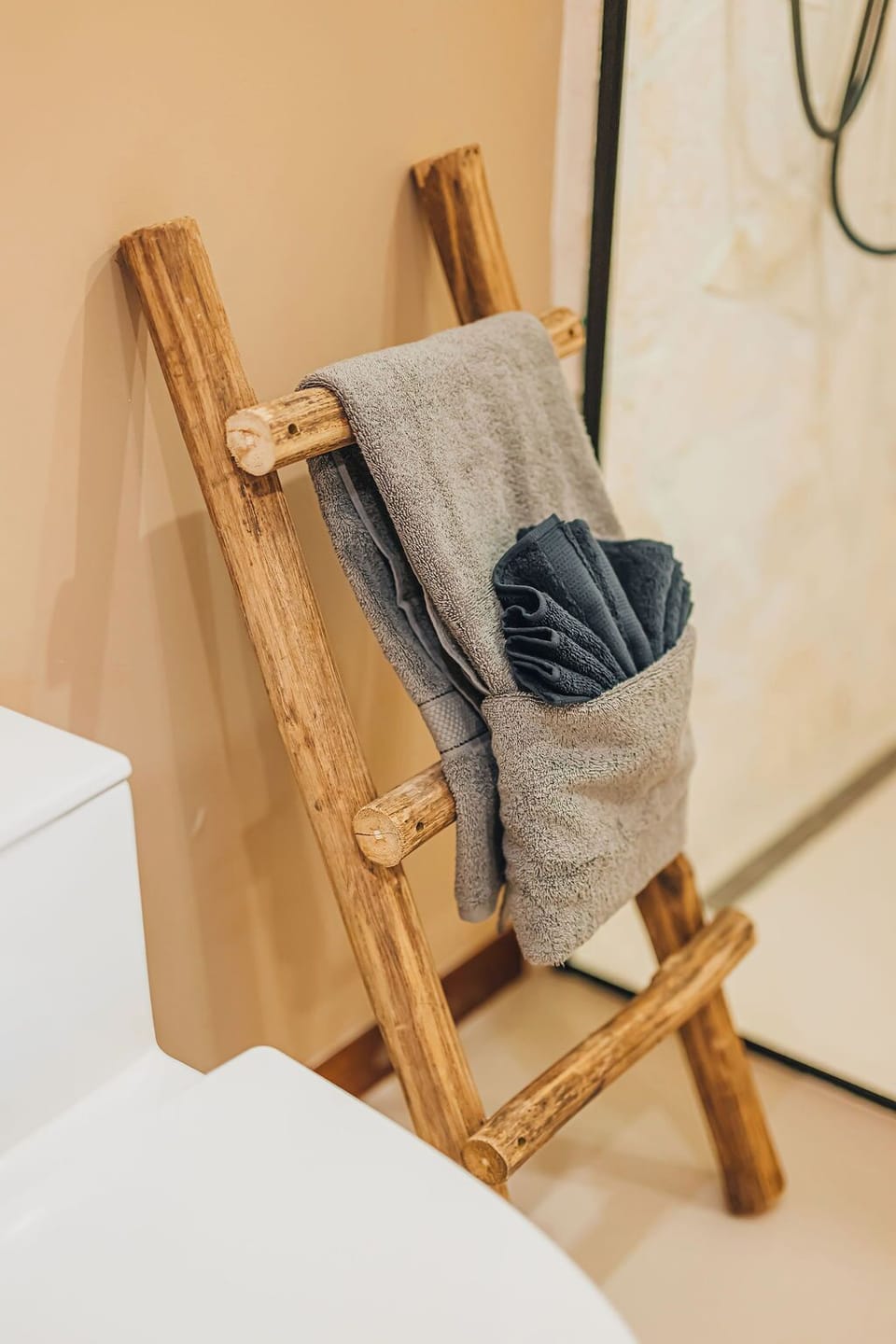 Rustic wooden towel ladder adds a warm, natural touch to the clean, modern bathroom design.

