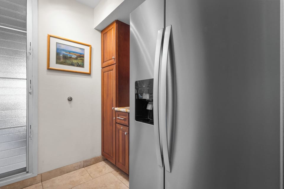 The modern stainless steel refrigerator and rich wood cabinetry create a functional, inviting kitchen space ready for your meal prep and morning coffee ritual.