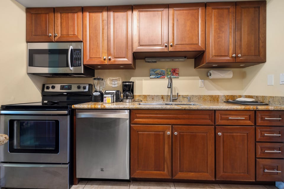Your fully equipped kitchen features warm wood cabinetry, granite countertops, and modern stainless steel appliances, ready for preparing home-cooked meals during your stay.